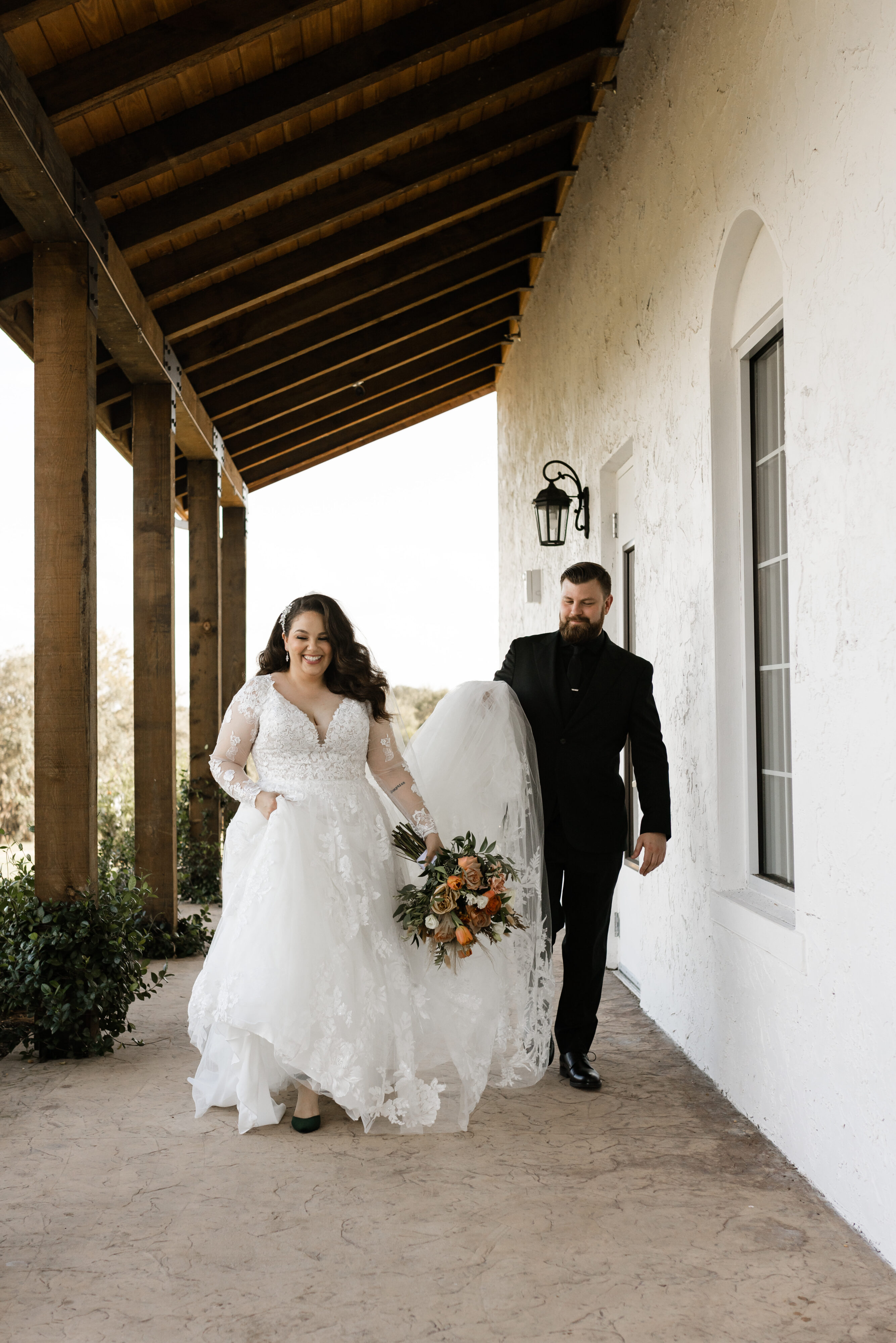 wedding photo of a brinde and groom walking together as the groom holds the dress